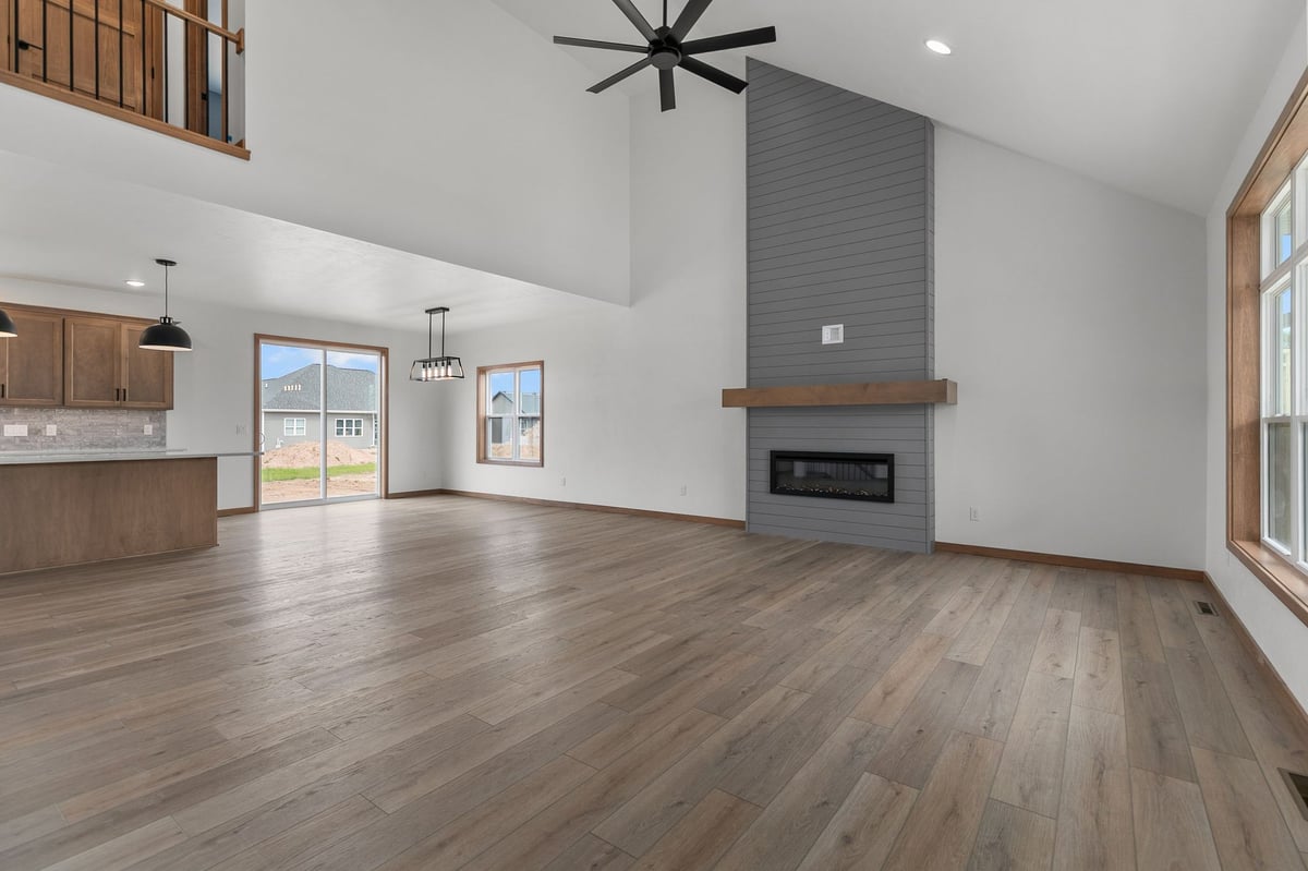 Open-concept living room with fireplace, vaulted ceiling, and wood floors in Appleton, WI