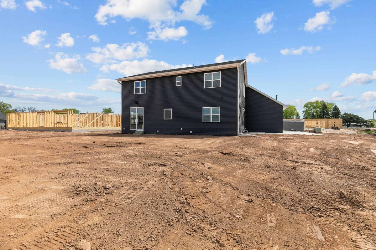 Rear view of modern black home exterior with large yard in a developing Appleton, WI neighborhood