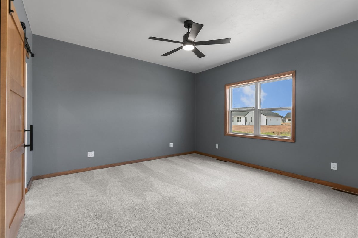 Spacious upstairs bedroom with vaulted ceiling and large window in a modern Appleton, WI home