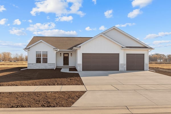 New single-story home in the Fox Cities with white siding, three-car garage, fresh driveway, and blue sky