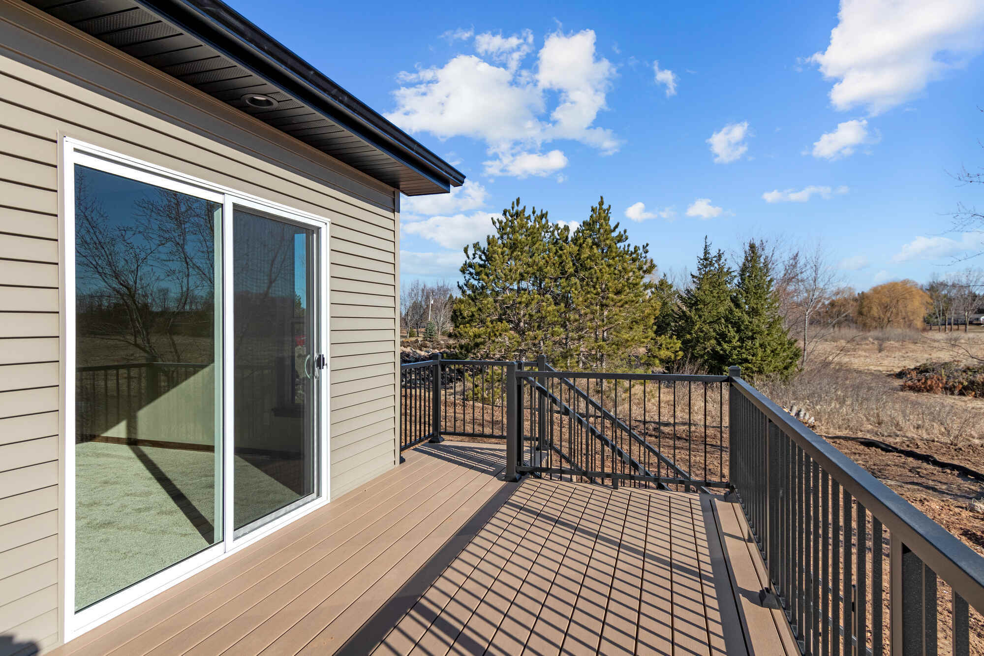 Sunny outdoor deck with railing on custom home in Appleton, WI by Midwest Design Homes