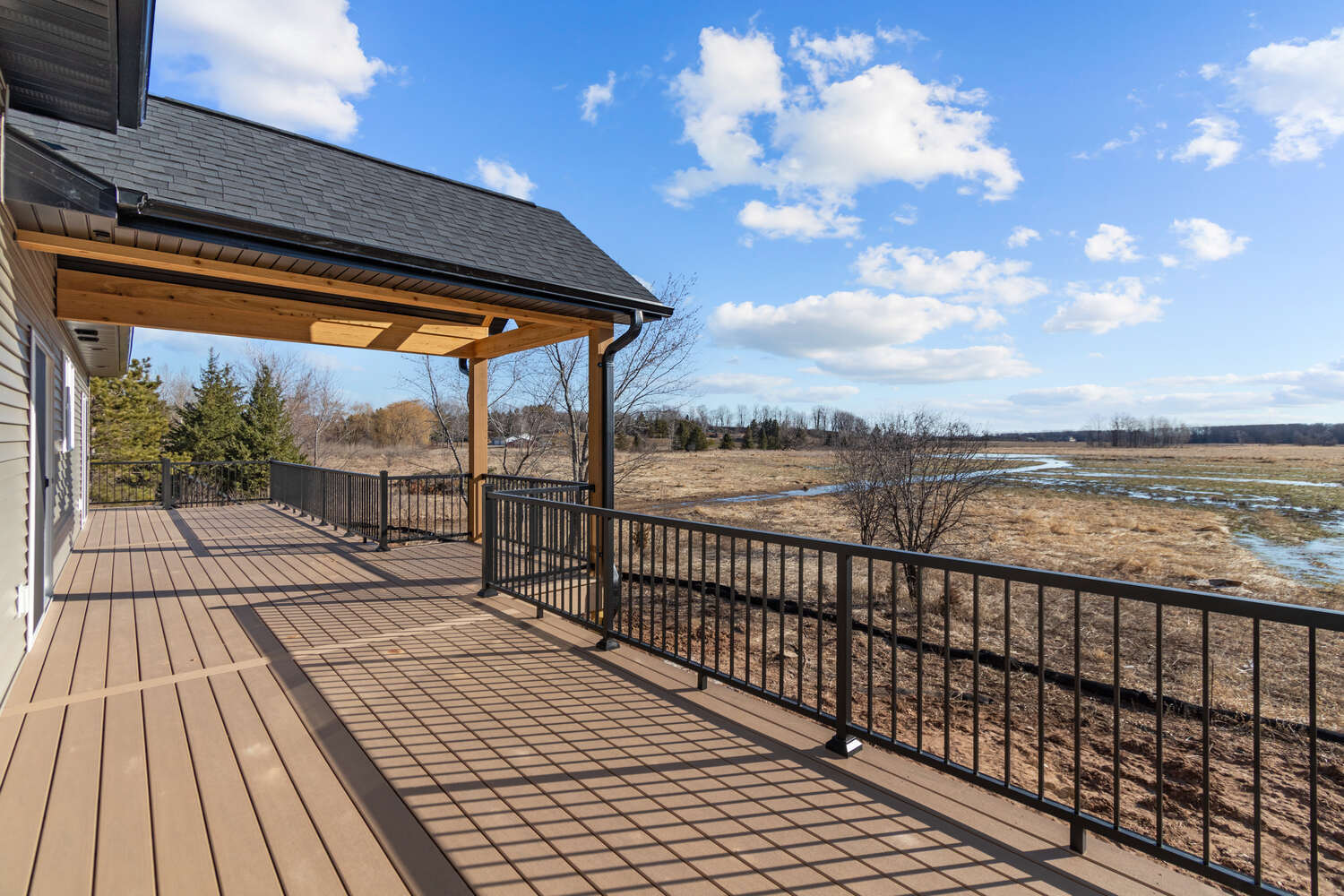 Covered patio deck with open field views in De Pere, WI custom home by Midwest Design Homes